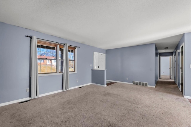 spare room with carpet, visible vents, and baseboards