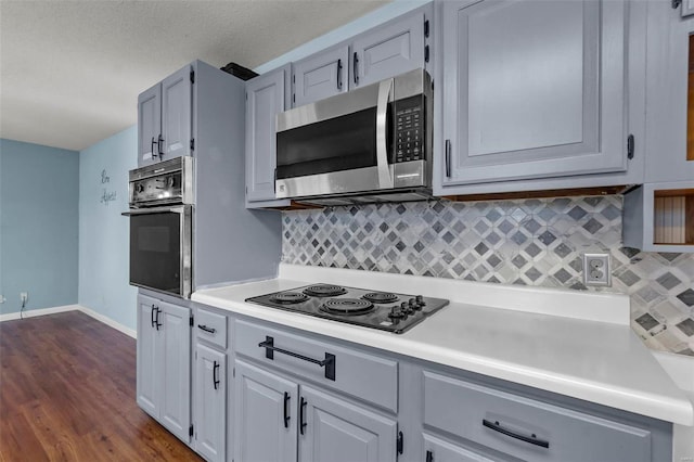 kitchen with black electric stovetop, light countertops, stainless steel microwave, decorative backsplash, and wall oven