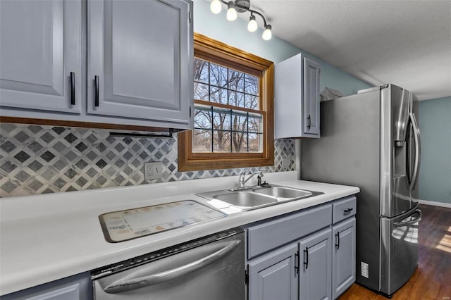 kitchen with stainless steel appliances, tasteful backsplash, gray cabinets, light countertops, and wood finished floors