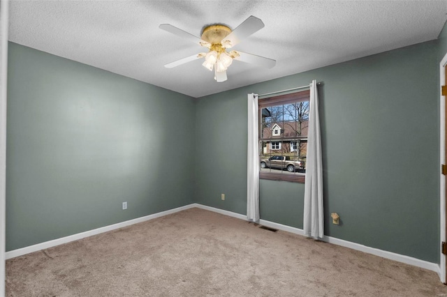 carpeted spare room featuring ceiling fan, a textured ceiling, visible vents, and baseboards