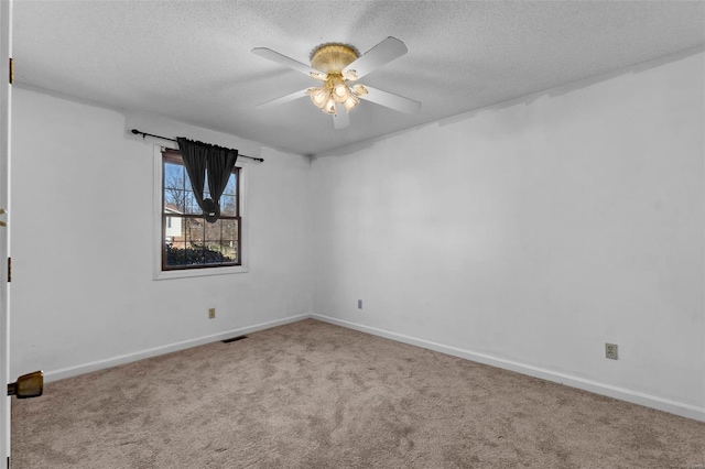 spare room featuring a ceiling fan, carpet, visible vents, and a textured ceiling