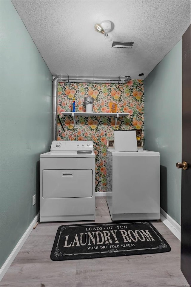 laundry area with laundry area, washer and clothes dryer, and light wood-type flooring