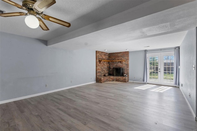 unfurnished living room featuring a textured ceiling, french doors, a fireplace, and wood finished floors