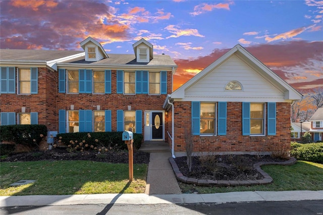 view of front of house with brick siding and a lawn