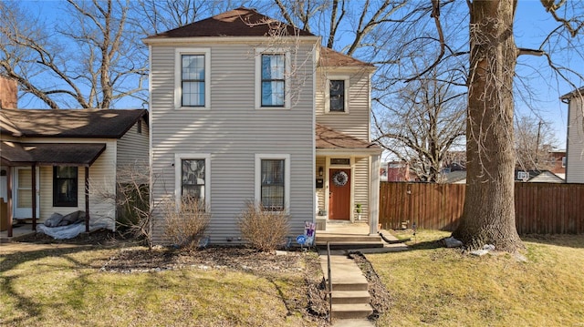 traditional-style home with a front lawn and fence