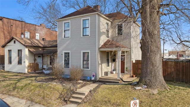 view of front facade with a front yard, fence, and a chimney