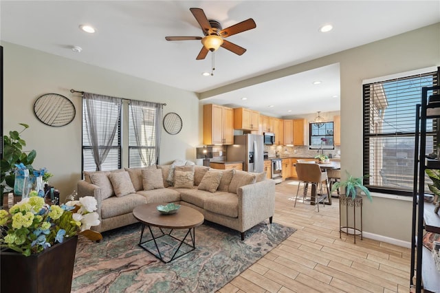 living room featuring baseboards, recessed lighting, a ceiling fan, and light wood-style floors