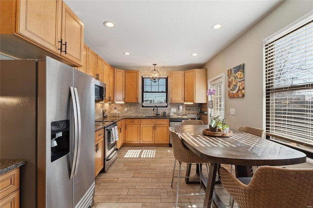 kitchen featuring tasteful backsplash, wood tiled floor, a chandelier, stainless steel appliances, and a sink