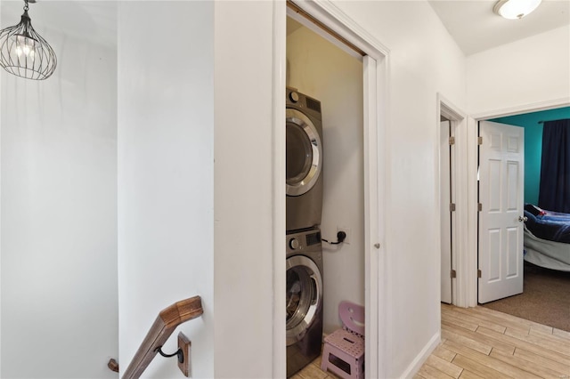 washroom with light wood-style floors, a chandelier, laundry area, and stacked washer / dryer