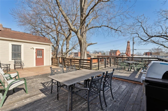 wooden deck with outdoor dining space and area for grilling