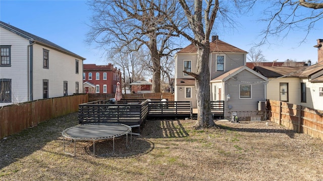 view of yard featuring a trampoline, a fenced backyard, a residential view, and a wooden deck