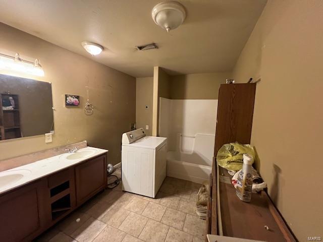 full bath with a bathing tub, a sink, visible vents, double vanity, and washer / dryer