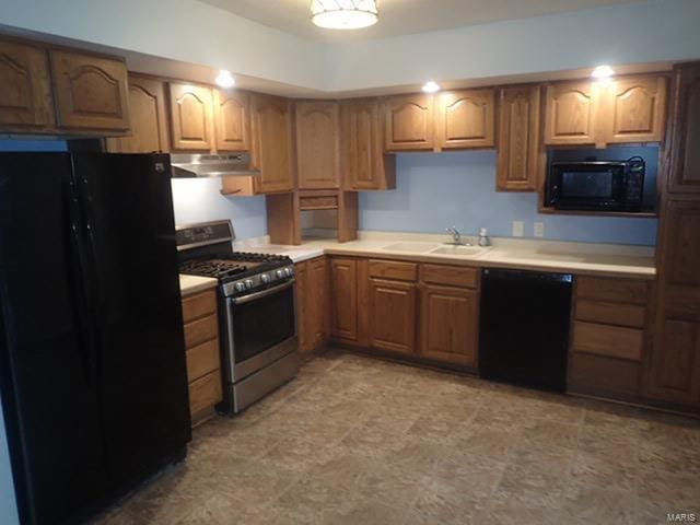 kitchen featuring brown cabinets, under cabinet range hood, light countertops, black appliances, and a sink