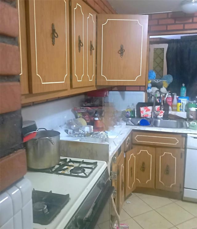 kitchen with brown cabinetry, dishwasher, light countertops, a sink, and light tile patterned flooring