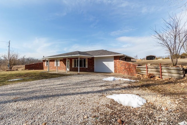 view of front of home with driveway, brick siding, an attached garage, and fence