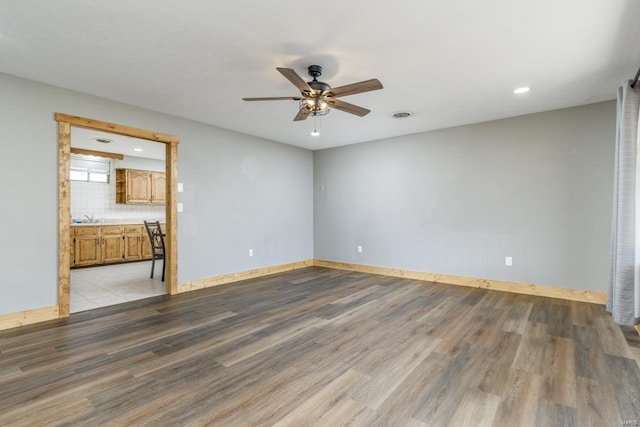 empty room with light wood-style flooring, visible vents, ceiling fan, and baseboards