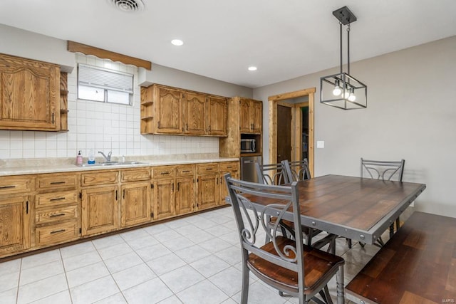 kitchen featuring visible vents, brown cabinets, a sink, and light countertops