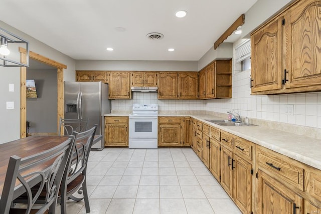 kitchen featuring white range with electric cooktop, visible vents, a sink, stainless steel fridge, and under cabinet range hood