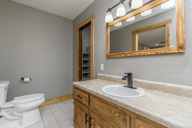 bathroom with toilet, tile patterned flooring, baseboards, and vanity