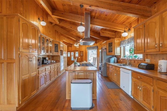 kitchen with a center island, wood walls, a sink, white appliances, and hardwood / wood-style flooring