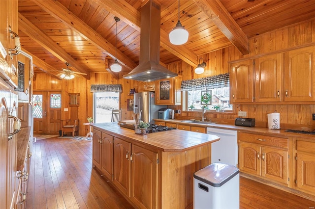 kitchen featuring high end refrigerator, island range hood, a center island, white dishwasher, and wood walls