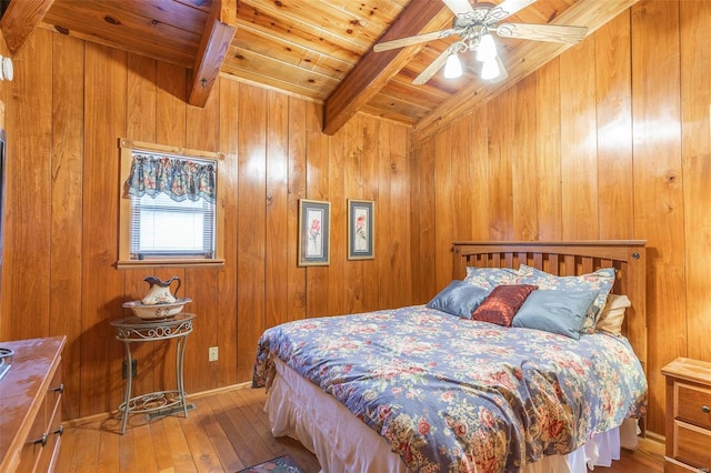 bedroom featuring ceiling fan, wooden ceiling, wooden walls, beam ceiling, and wood-type flooring