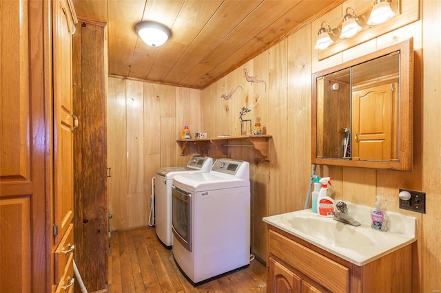 laundry area featuring wooden ceiling, washing machine and dryer, wood walls, wood finished floors, and a sink