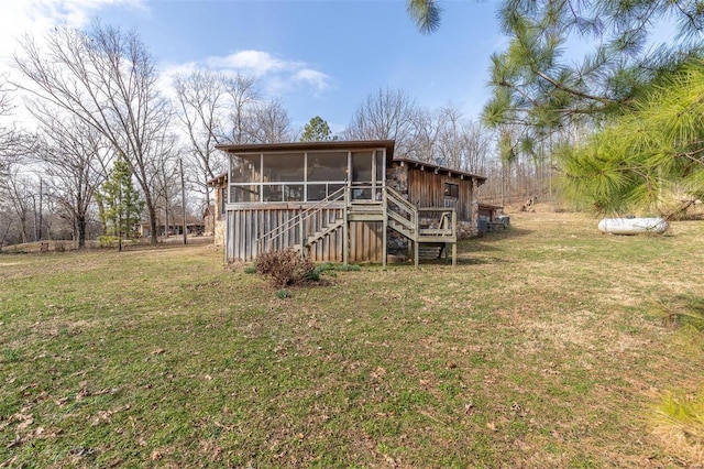 back of property with a sunroom, a lawn, and stairway