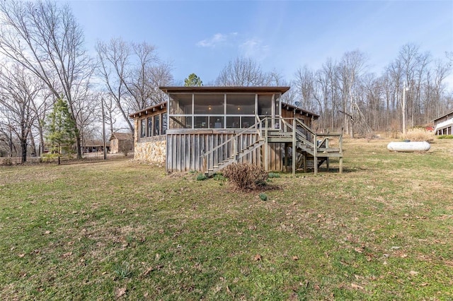 rear view of property featuring a yard, stairway, and a sunroom