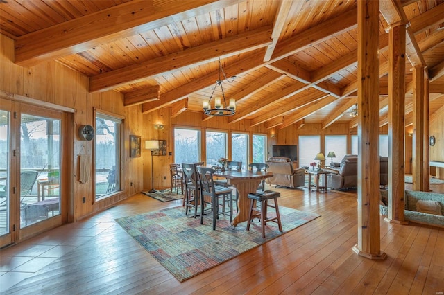 dining space with a healthy amount of sunlight, light wood-style floors, beamed ceiling, and an inviting chandelier