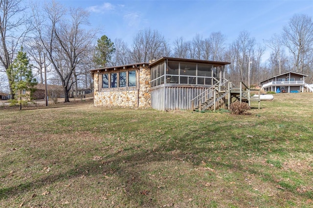 exterior space featuring a sunroom, stone siding, stairway, a front lawn, and a chimney