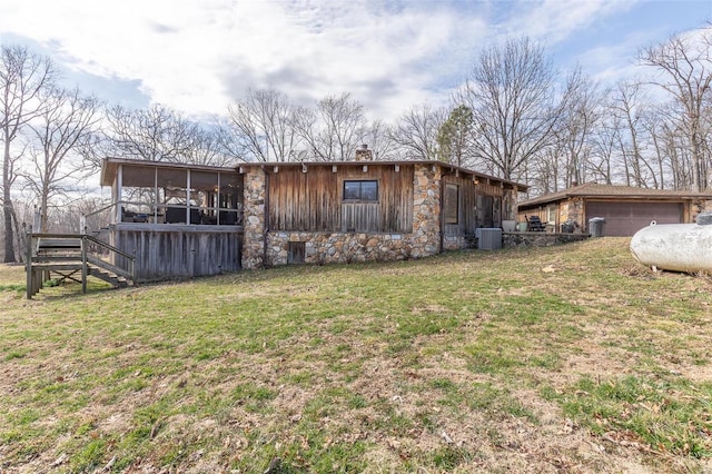 rear view of property featuring an outbuilding, a sunroom, stairs, a yard, and a chimney