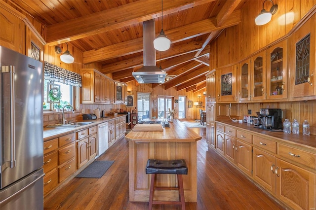 kitchen featuring high end fridge, a sink, wooden walls, wood counters, and a kitchen island