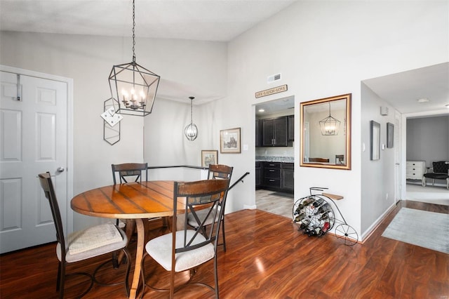 dining area with light wood finished floors, baseboards, visible vents, high vaulted ceiling, and a notable chandelier