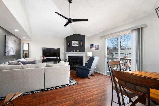 living room featuring lofted ceiling, ceiling fan, a textured ceiling, dark wood-style flooring, and a fireplace