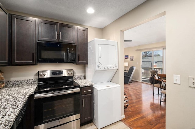 kitchen featuring black microwave, a textured ceiling, light wood-style floors, stacked washing maching and dryer, and stainless steel range with electric stovetop