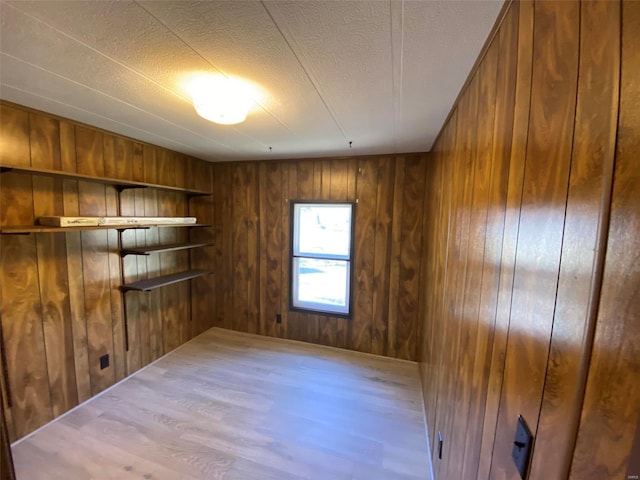 empty room featuring wooden walls, a textured ceiling, and wood finished floors