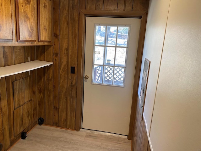 doorway to outside featuring light wood-style flooring and wooden walls