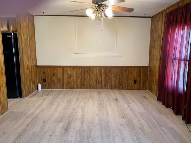 spare room featuring a wainscoted wall, wood walls, and wood finished floors