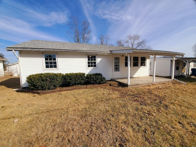 back of house featuring a patio area, a shingled roof, and a yard