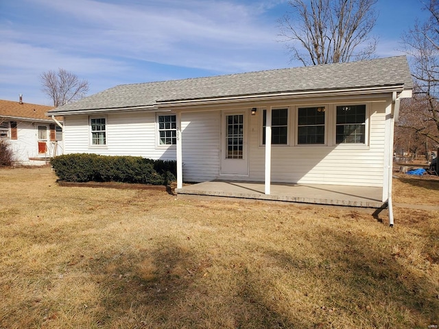 rear view of property with roof with shingles, a patio, and a yard