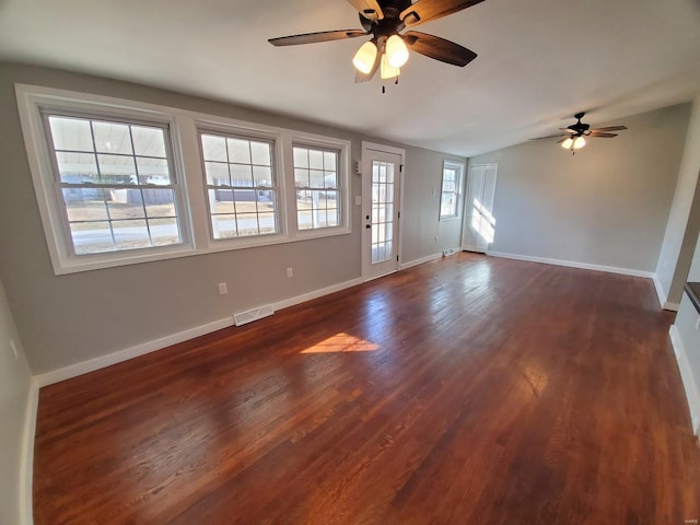 unfurnished living room with dark wood-style floors, visible vents, vaulted ceiling, and baseboards