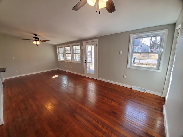 unfurnished living room featuring dark wood-style floors, ceiling fan, visible vents, and baseboards