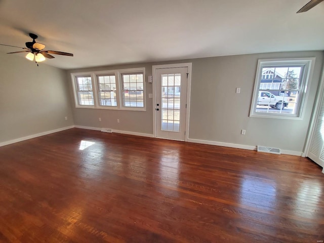 spare room with a wealth of natural light, dark wood-style flooring, visible vents, and baseboards