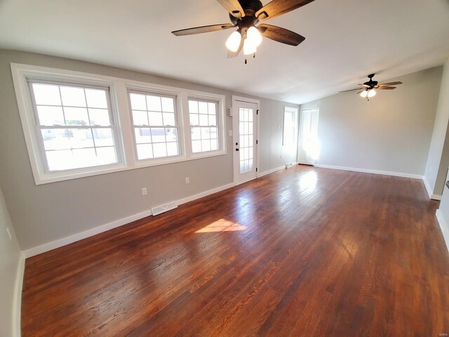 unfurnished living room with dark wood-style flooring, visible vents, and baseboards