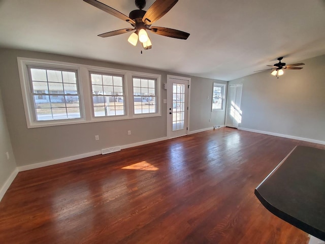 unfurnished living room with dark wood-style flooring, visible vents, a ceiling fan, vaulted ceiling, and baseboards