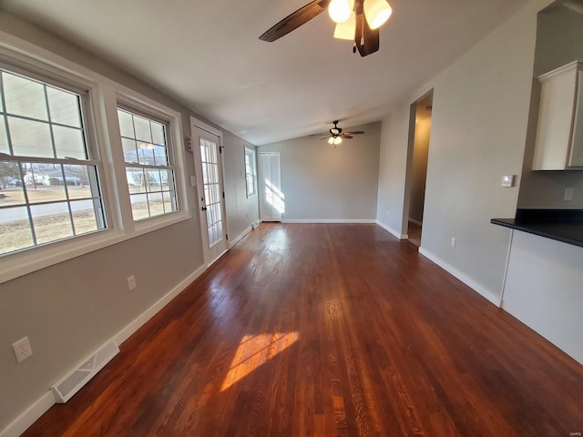 unfurnished living room featuring baseboards, visible vents, a ceiling fan, lofted ceiling, and dark wood-style floors