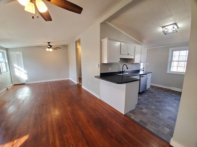 kitchen featuring white cabinets, dark countertops, lofted ceiling, stainless steel dishwasher, and a sink