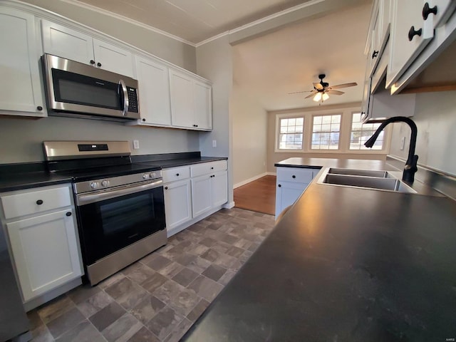 kitchen with dark countertops, white cabinetry, appliances with stainless steel finishes, and a sink