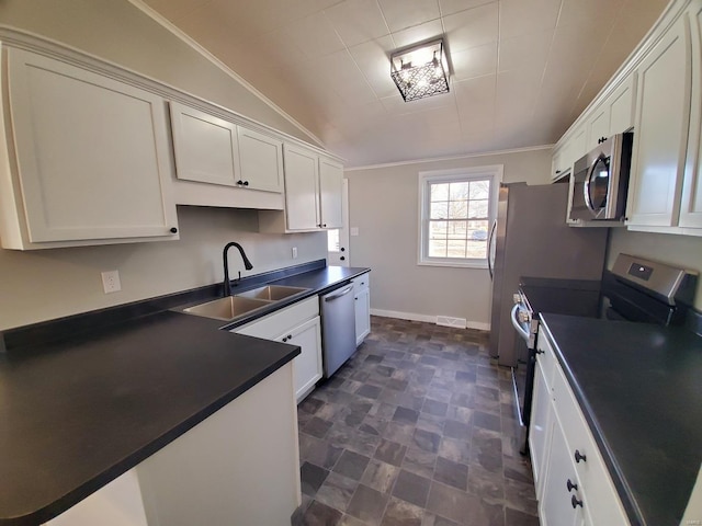 kitchen with stainless steel appliances, dark countertops, a sink, and white cabinetry